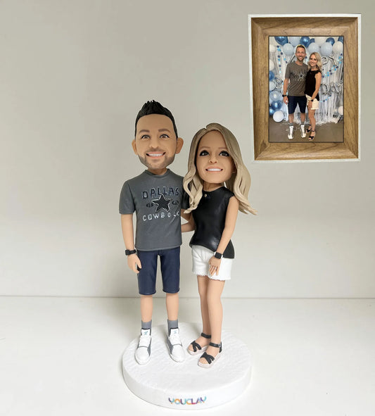 Couple bobbleheads in a Cowboys tee and black top, shown beside the framed photo they were sculpted from