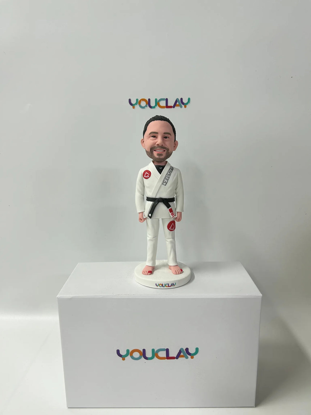 Custom bobblehead of a bearded man in a white jiu-jitsu gi with a black belt, standing barefoot