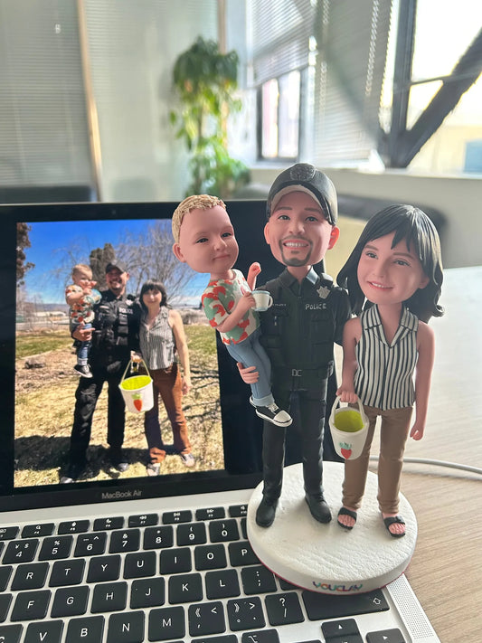 Police officer holding a toddler beside a woman with a bucket, set of 3 bobbleheads in front of their photo