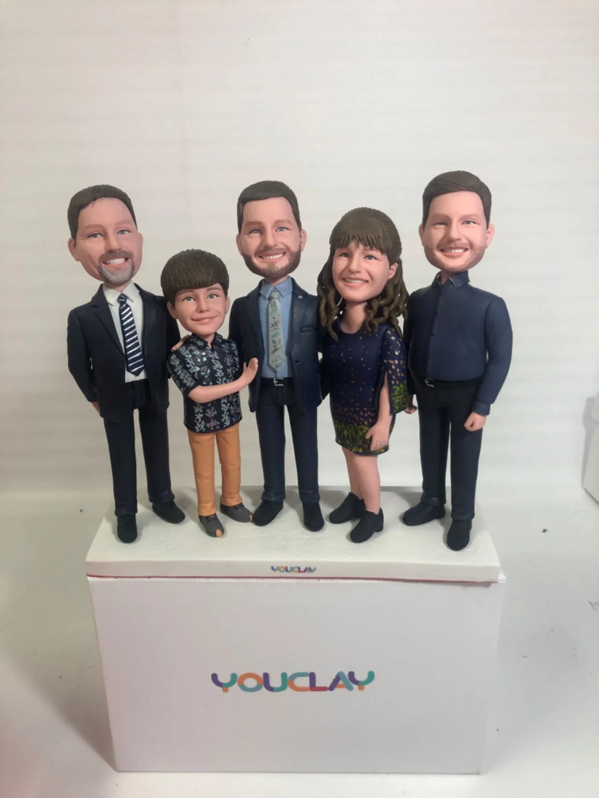 Three men in suits with a woman in a sequin dress and a boy, a dressy family of five figurines