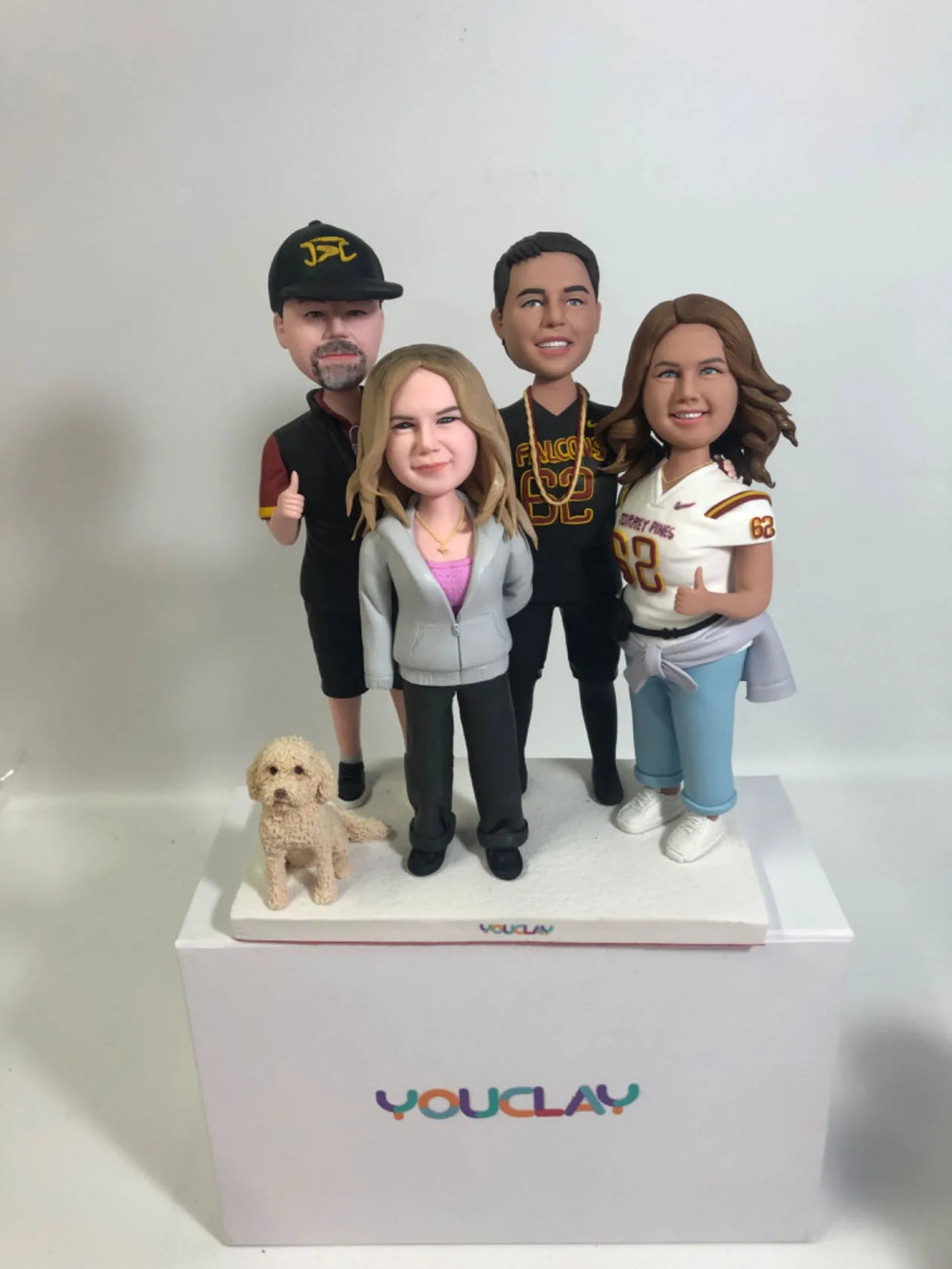 Family of five in sports gear and a hoodie with a small golden doodle at their feet, in clay