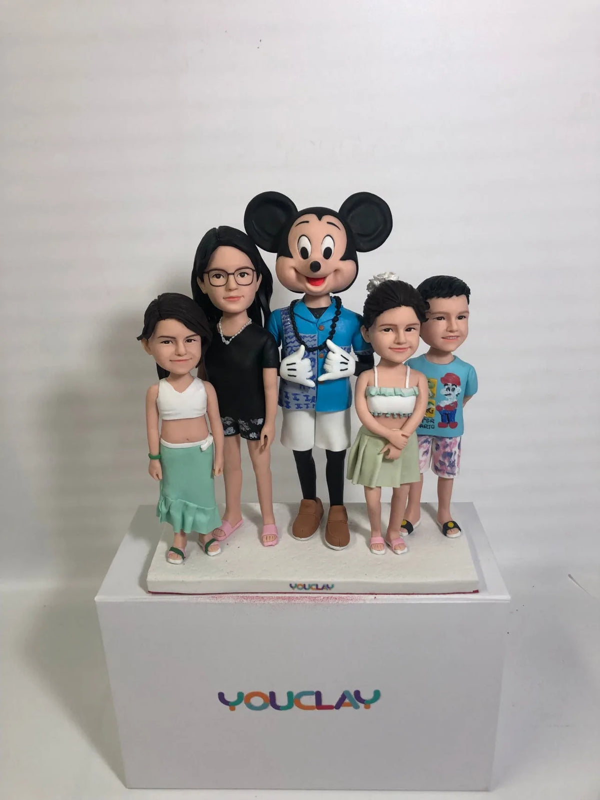 Four kids in summer outfits standing with a Mickey Mouse figure, a Disney-themed family set