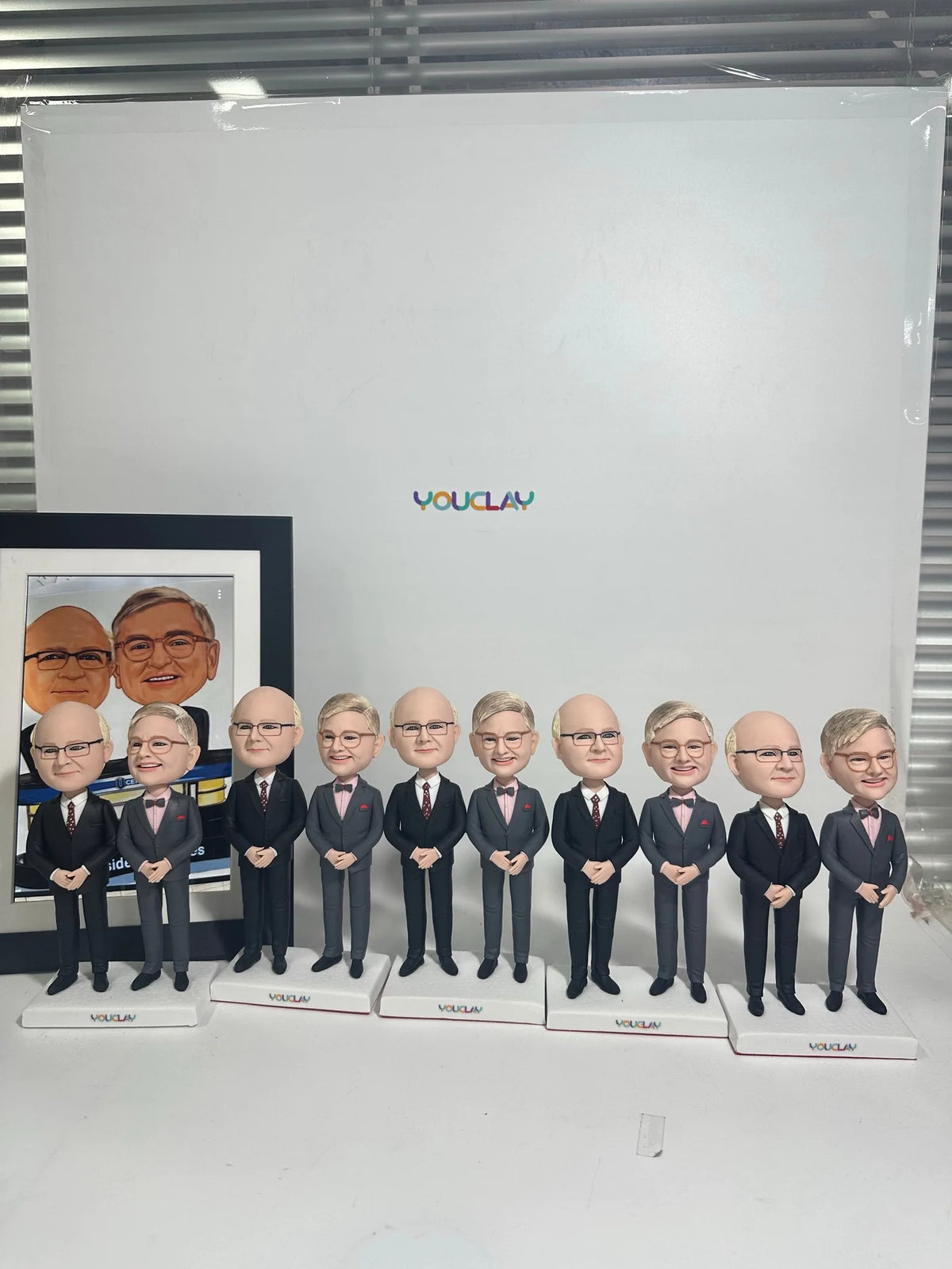 Ten men in matching gray suits on separate bases, sculpted from a framed office photo