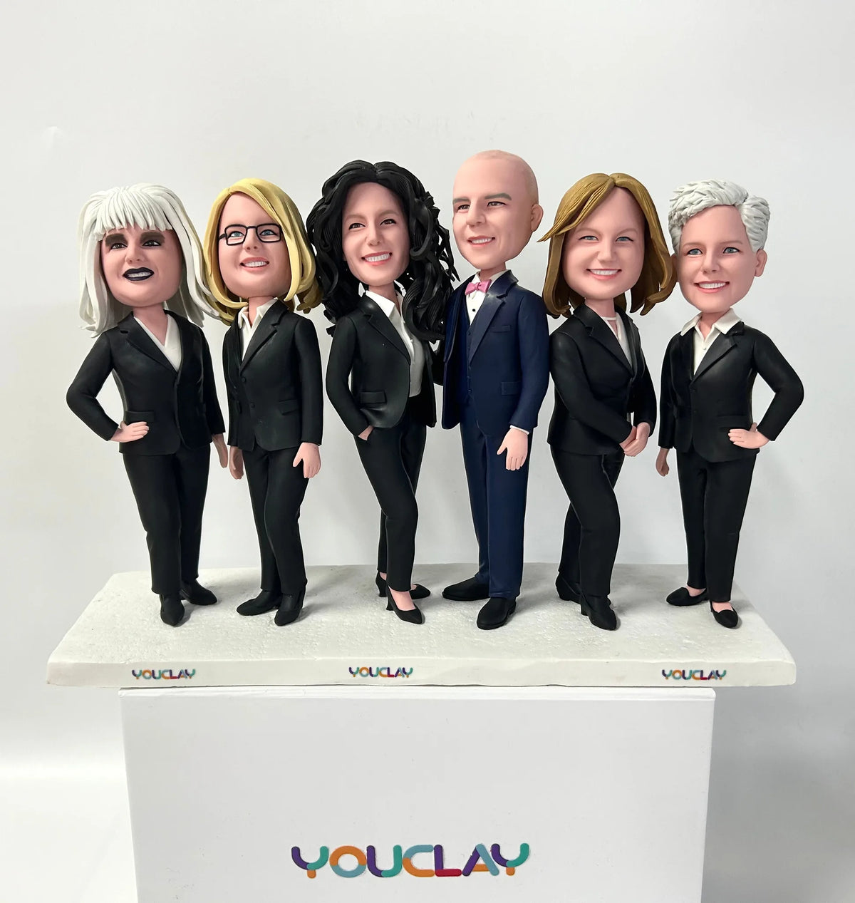Six coworkers in black business suits posing confidently, a group of custom bobbleheads