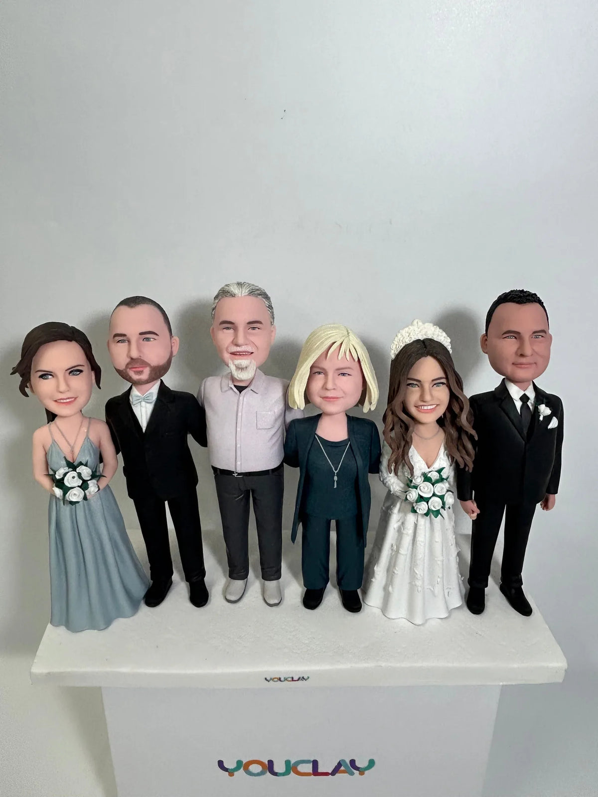 Wedding group of six with the bride in white, a bridesmaid in blue and men in black suits