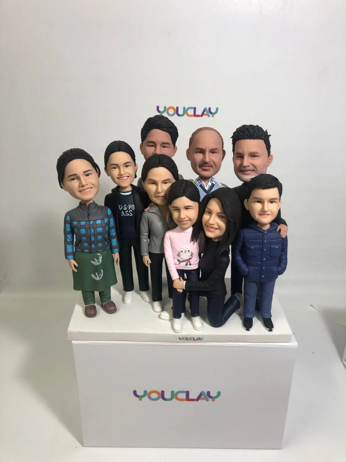 Nine family members of all ages crowded together, some kneeling, a big clay figurine group